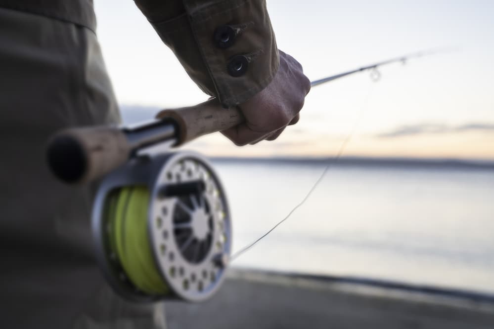 Man about ready to fish with fly fishing reel.